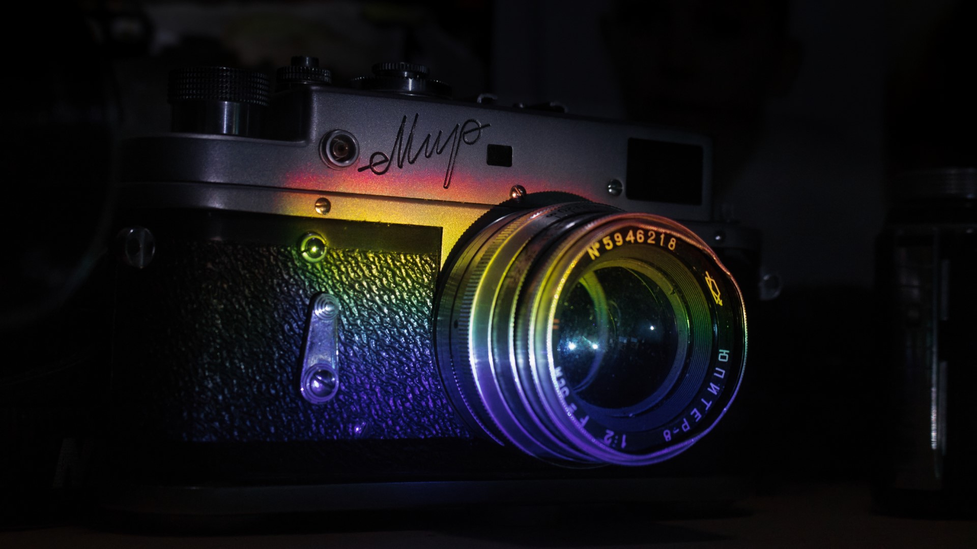 A soviet-era film camera on a shelf with a rainbow made using dispersion cast on it